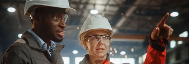 People wear hardhats in a warehouse.