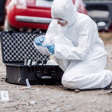 forensic scientist collects evidence at a crime scene